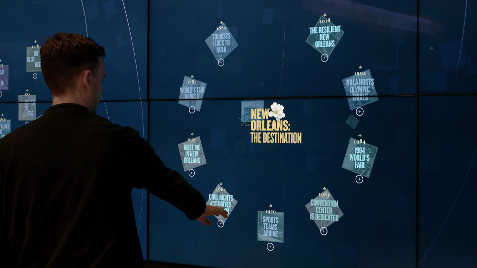 Visitor pointing at the interactive media wall in the convention center lobby