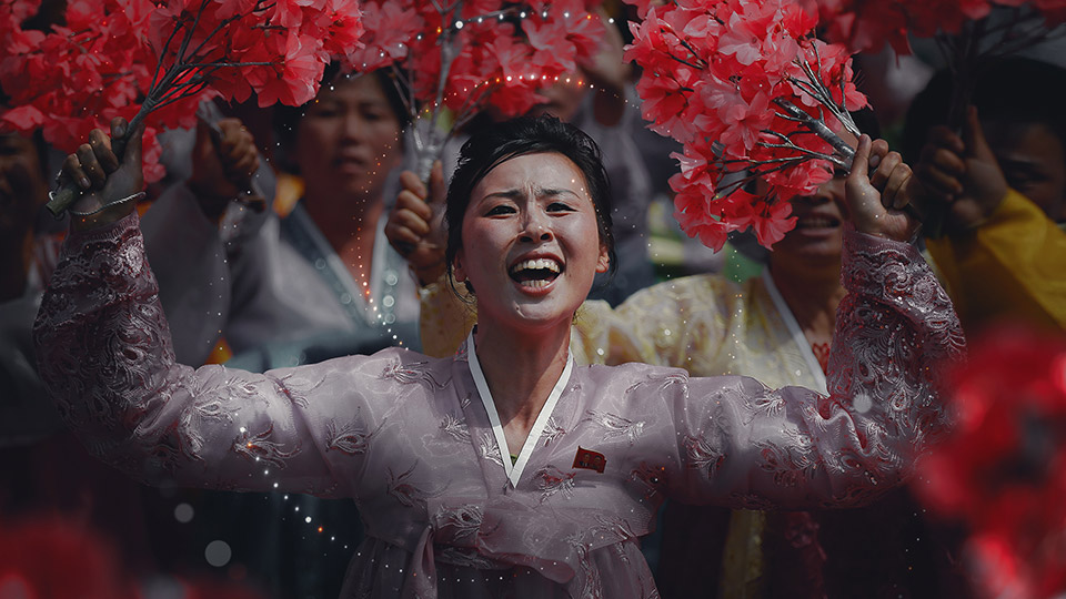 Performer holding red blossoms, overlaid with the redesigned particle treatment