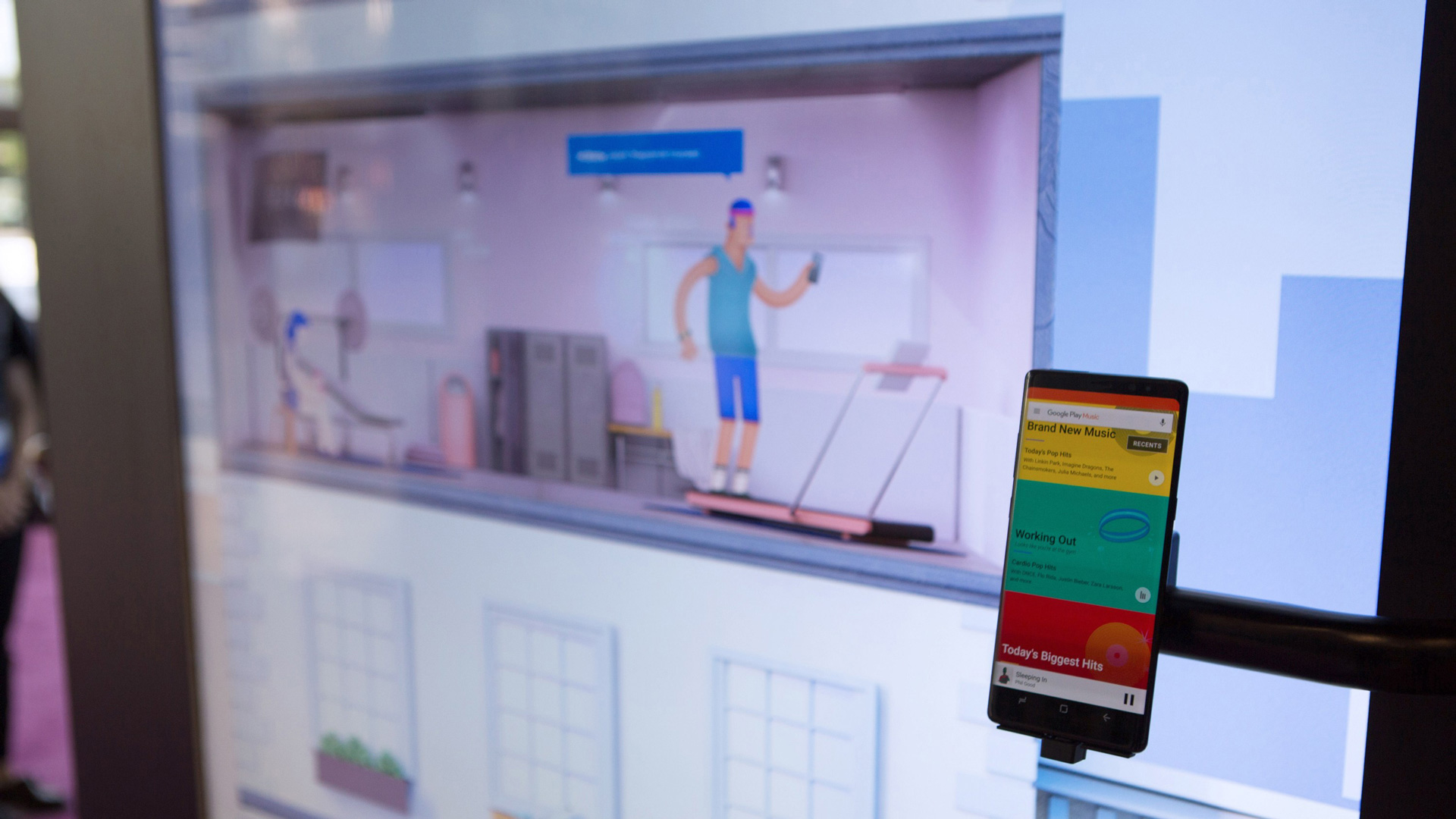 Close-up of the wall screen showing a home workout scene with a phone mounted beside it