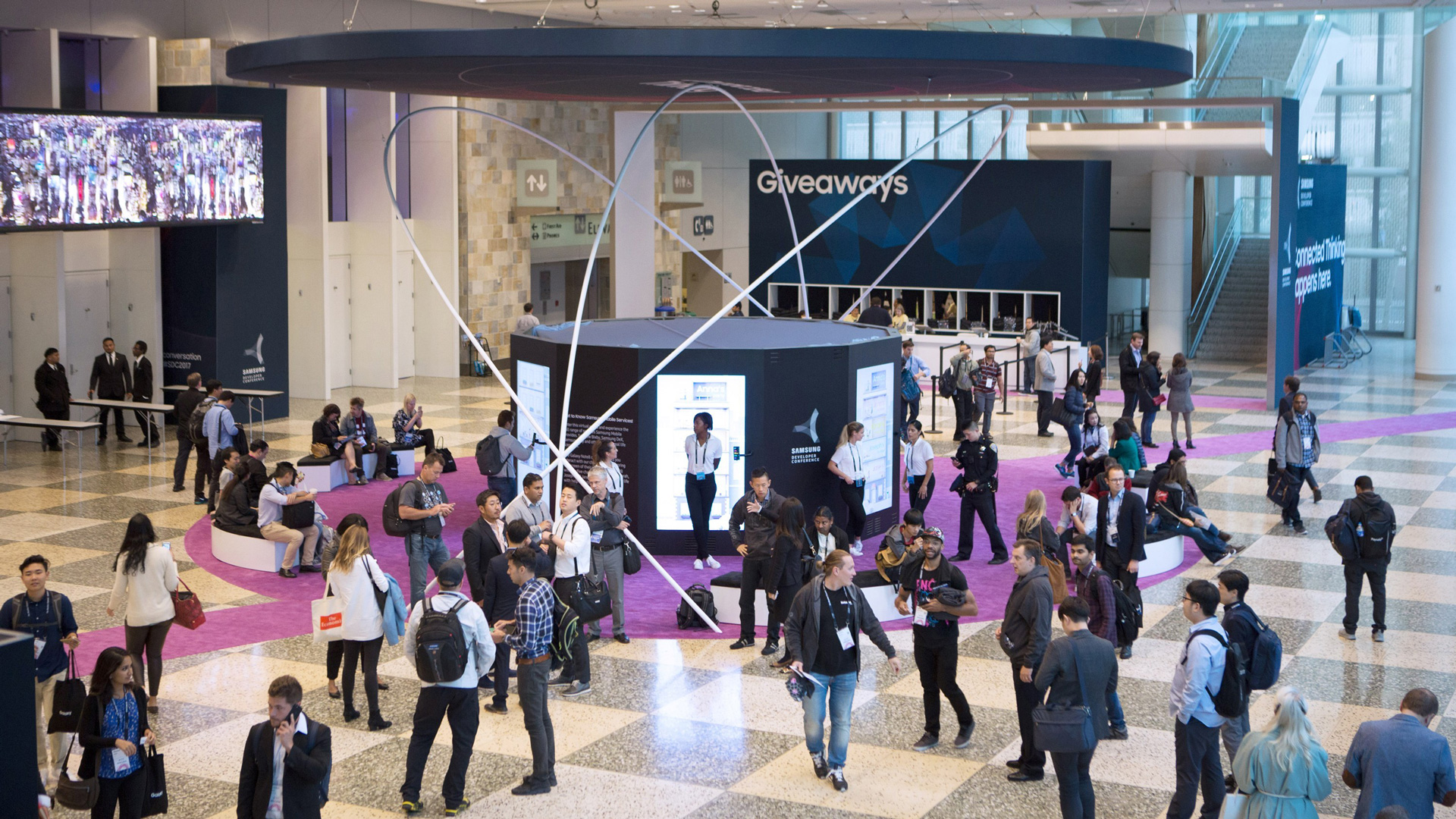 Wide view of the installation with attendees filling the lobby floor